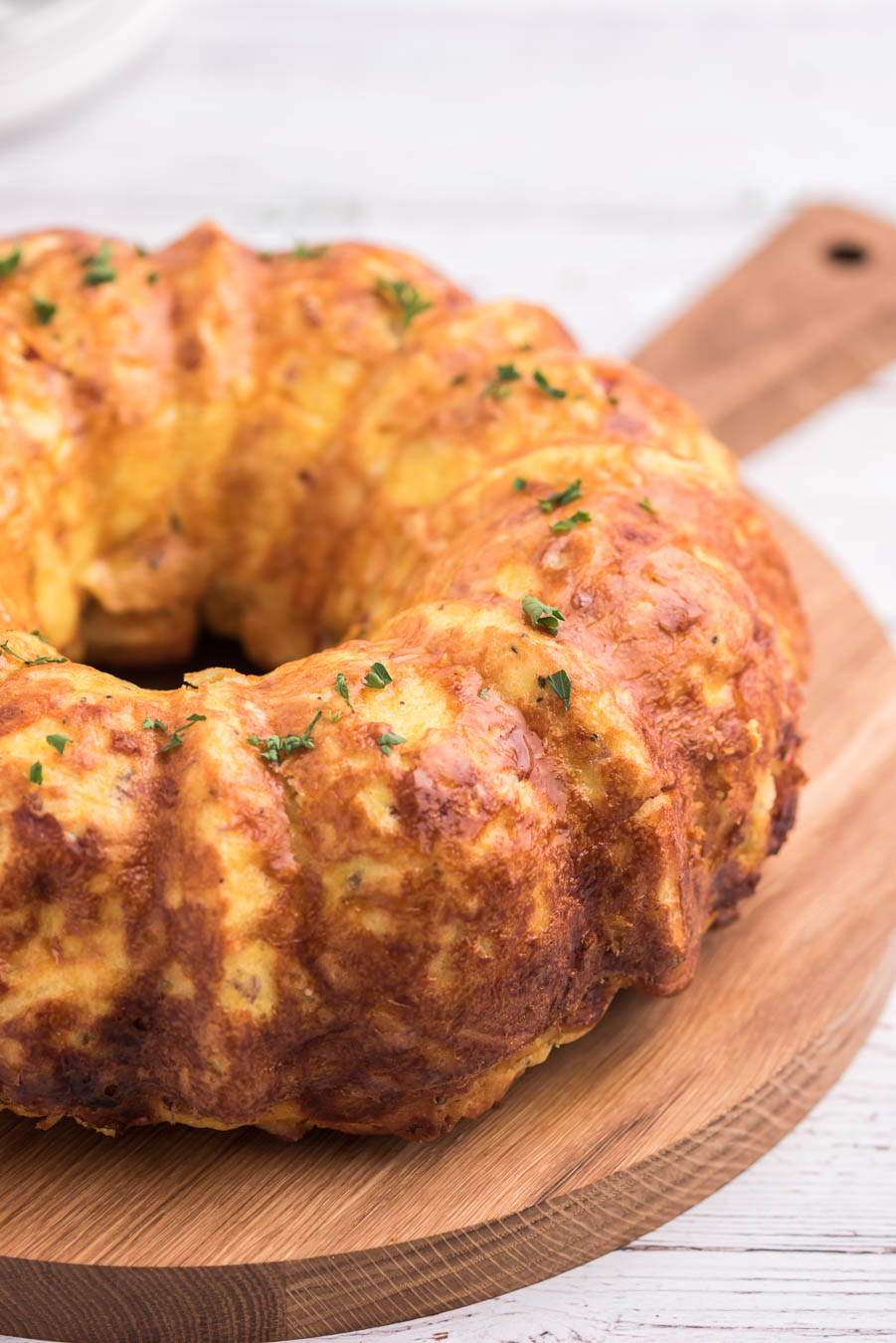 breakfast casserole removed from bundt pan and placed on wooden serving board. parsley garnish.