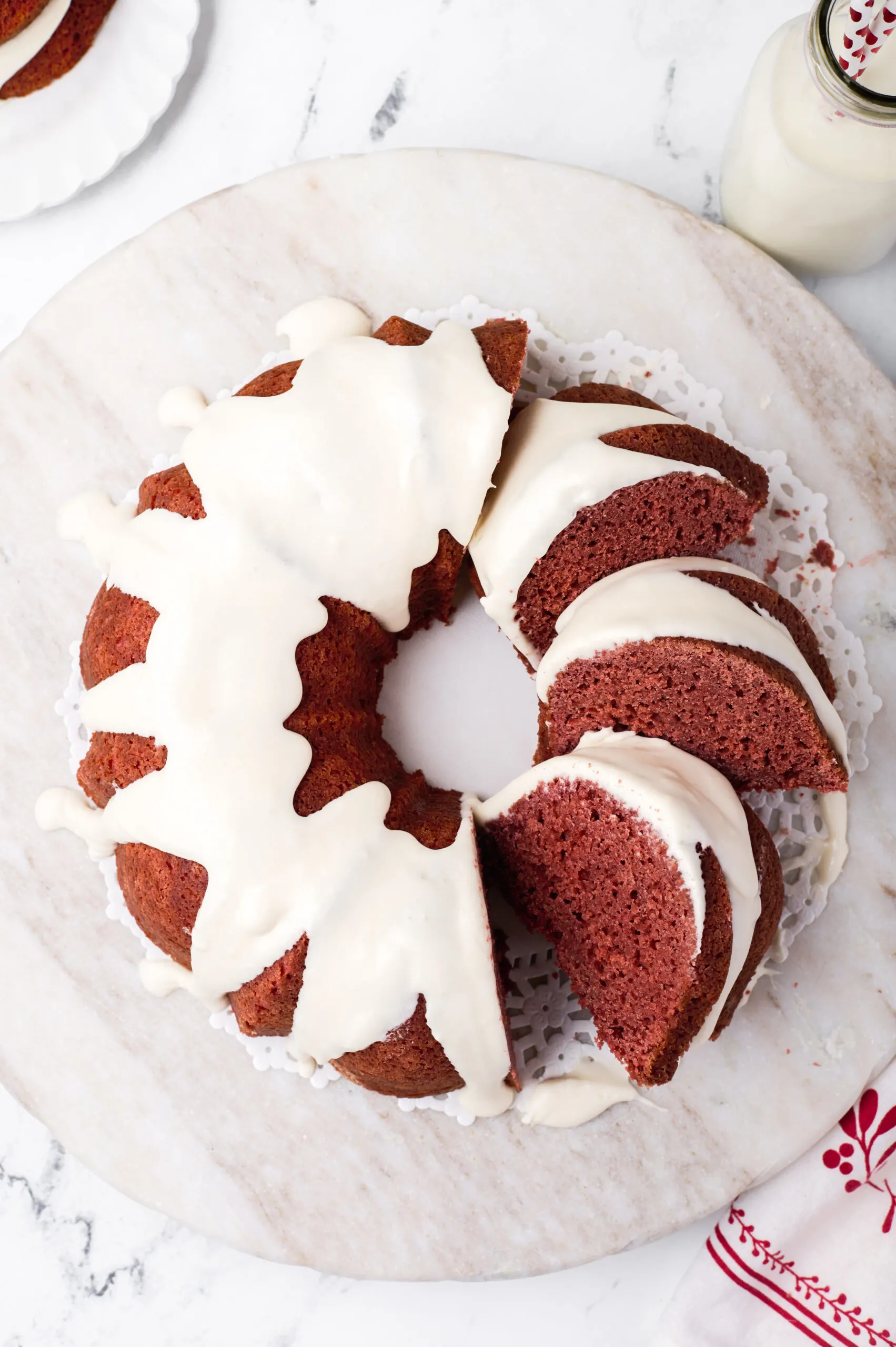 whole red velvet bundt cake on a light wood cutting board with three slices on the right side fanned out