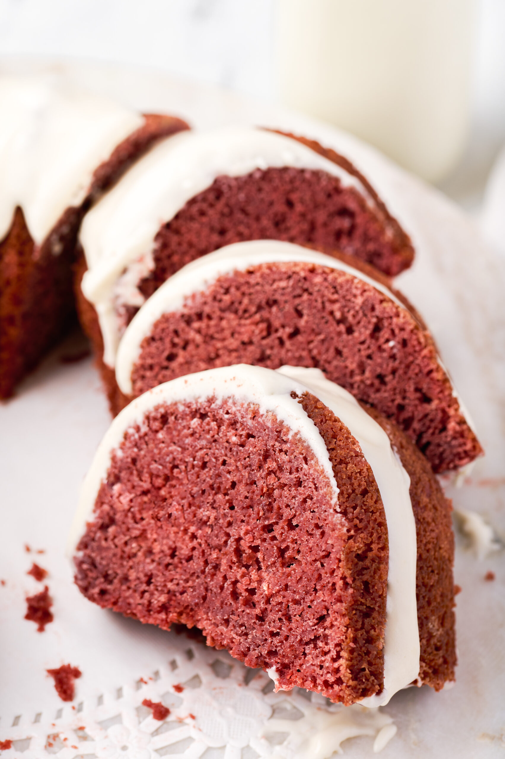 close up image of three cut slices of a red velvet bundt cake on a lace doily