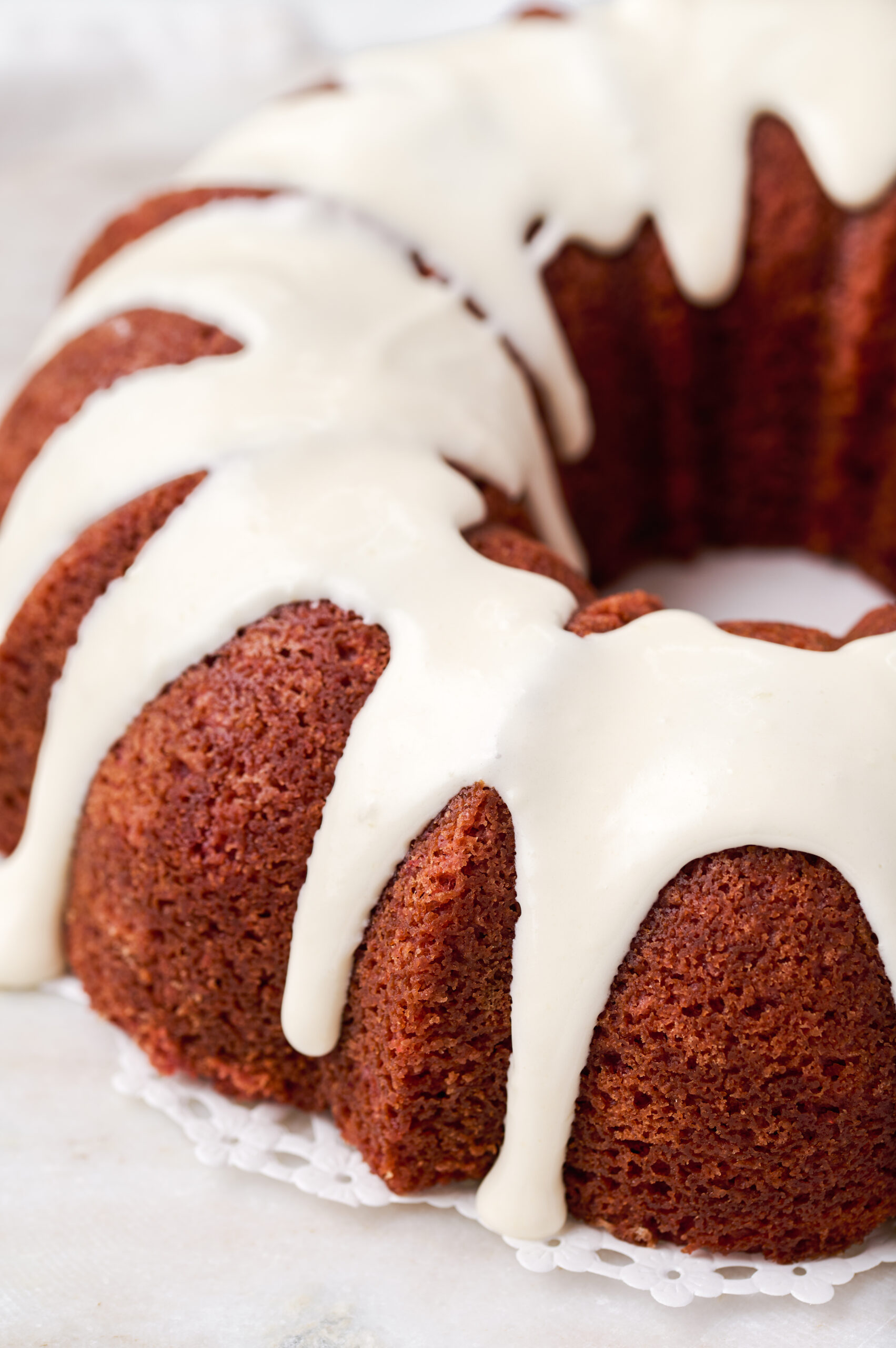 off center image of half of a frosted red velvet bundt cake pan on a lace doily