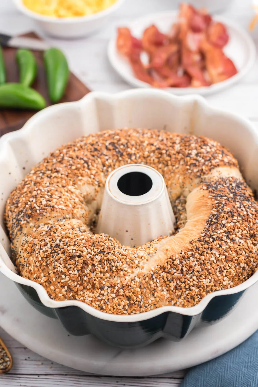 baked jumbo everything bagel in a bundt pan on a marble cake stand