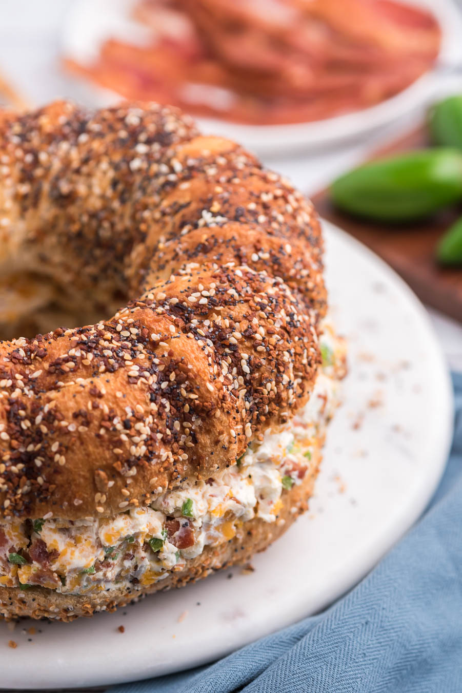 off center image of a jumbo everything bagel filled with cream cheese