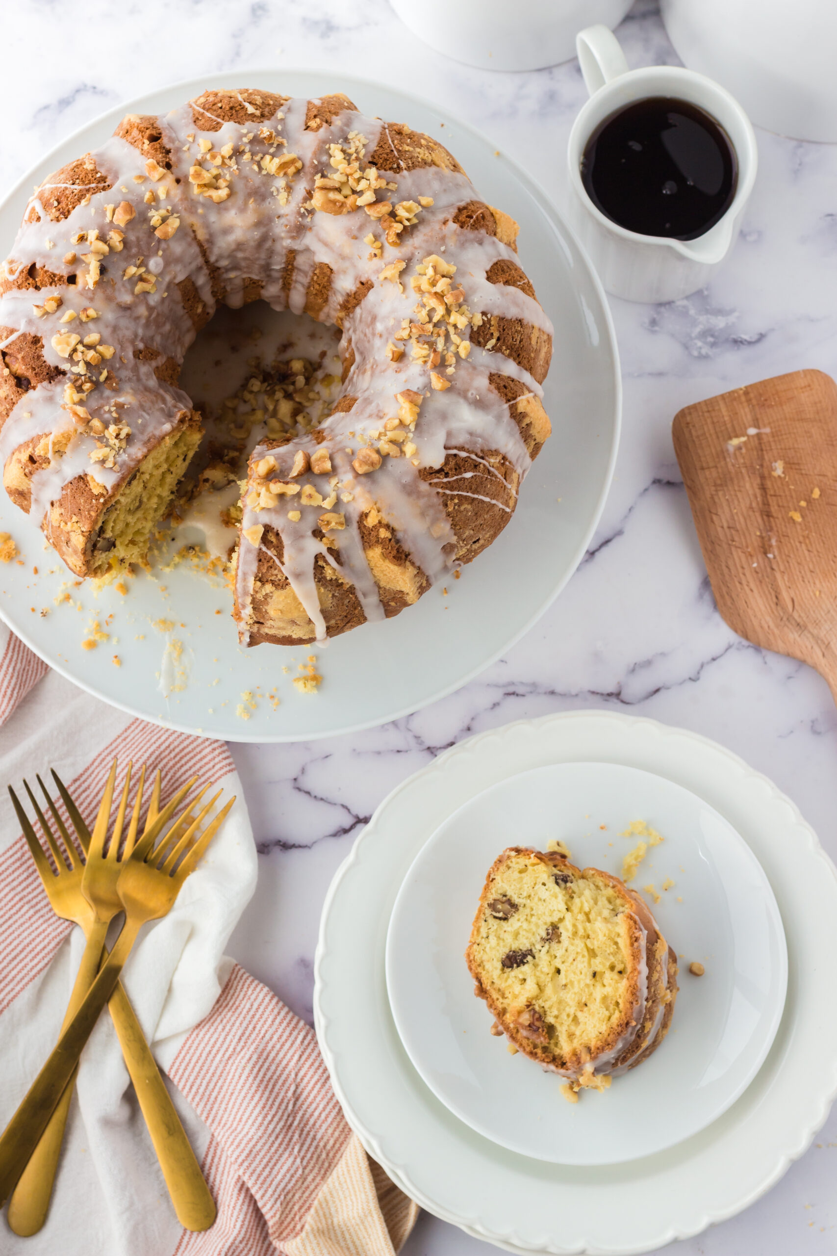 birds eye image of a maple walnut bundt cake on a white cake stand with a slice on a plate